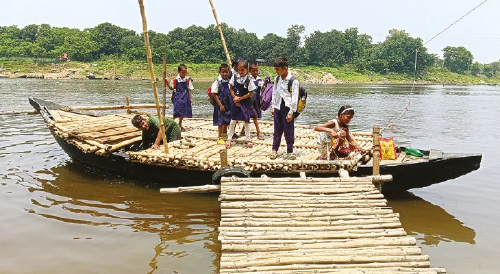 A minor salior is helping primary school students to cross river in malda 